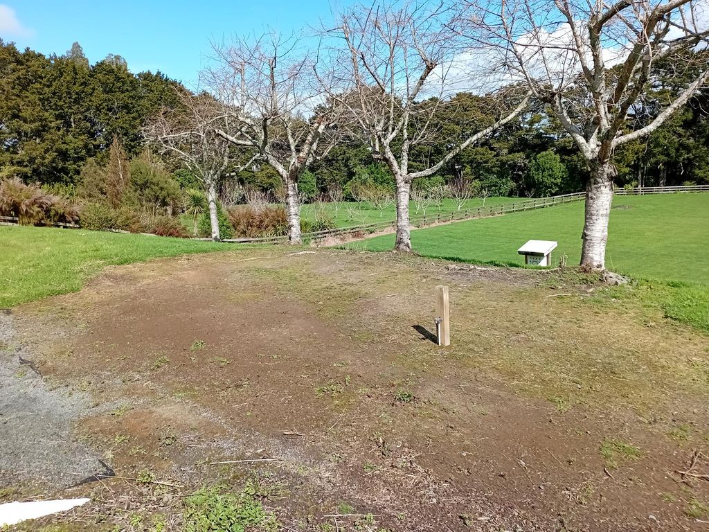 Cleared and shaped ground alongside a lawn and trees