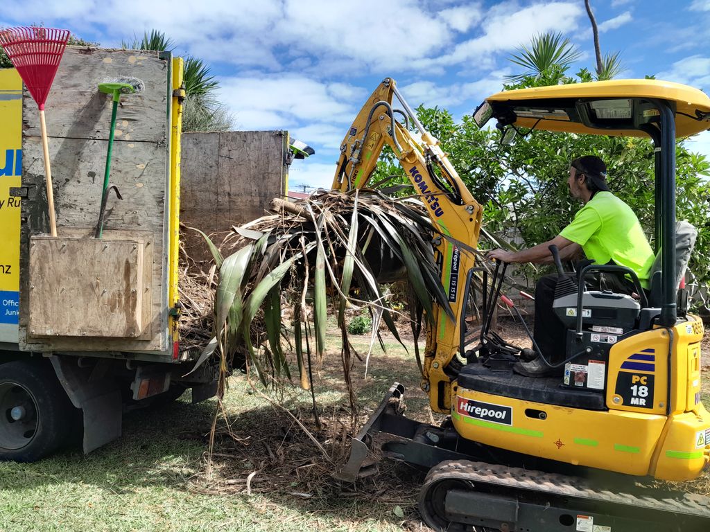 Operator loading a bundle of uprooted vegetation into a removal truck